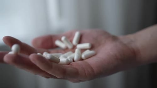 Hand Holding White Medicinal Capsules Indoors