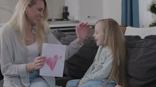 Little Girl Giving Drawing to Happy Mother