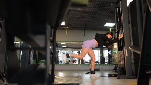 A Fit Woman Performs Intense Leg Exercises with Advanced Gym Equipment Demonstrating Strength and