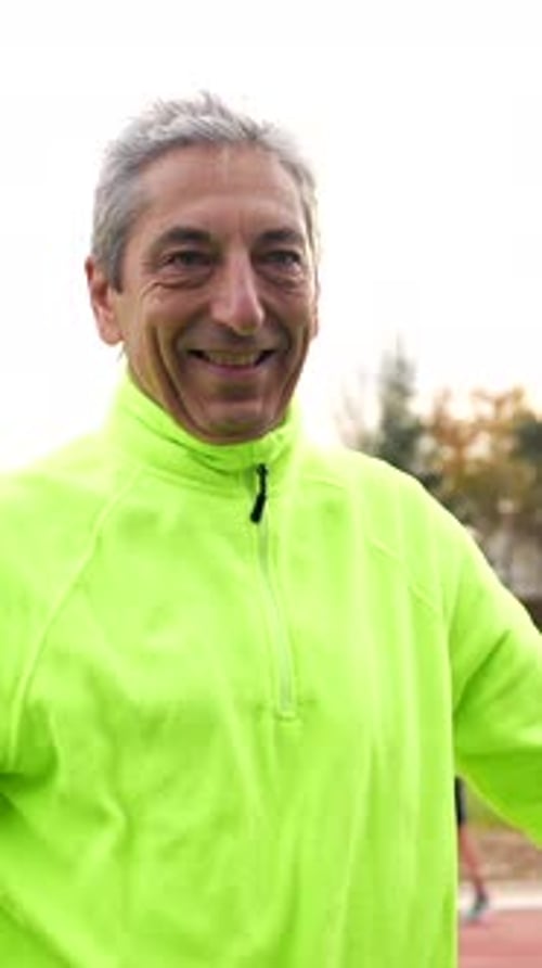 Smiling Adult Stretching on a Track Field