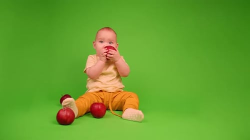 Happy Infant Eats an Apple on Green Screen
