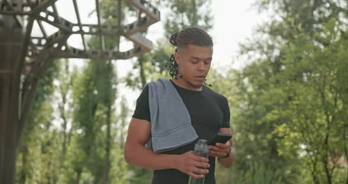 Fit Man Uses Phone in Sunny Park