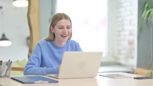Woman Cheers at Desk While Using Laptop