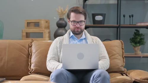 Man on Couch Working on Laptop and Thumbs Up