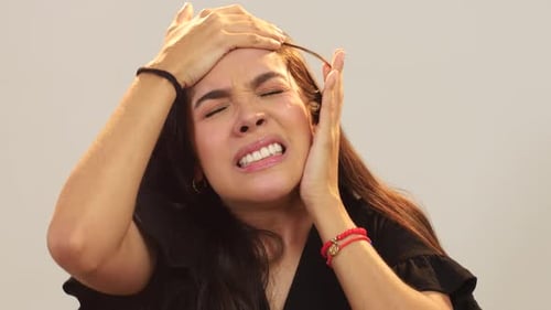 Close up of young woman suffering headache and holding her head
