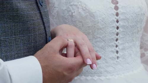 39Der Bräutigam hält die Hand der Braut mit einem Ehering in der Hand.
