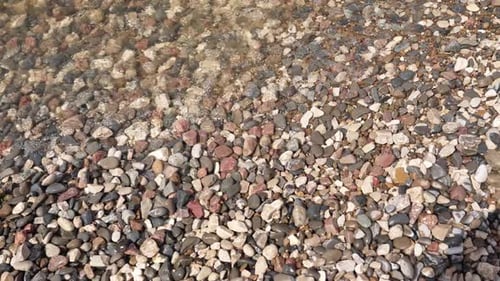 Gentle Waves Wash Over Colorful Pebble Shore at Tranquil Seaside