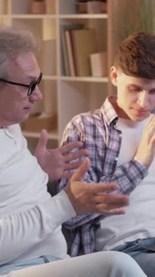 Man and Teenager Use Laptop Together in Home
