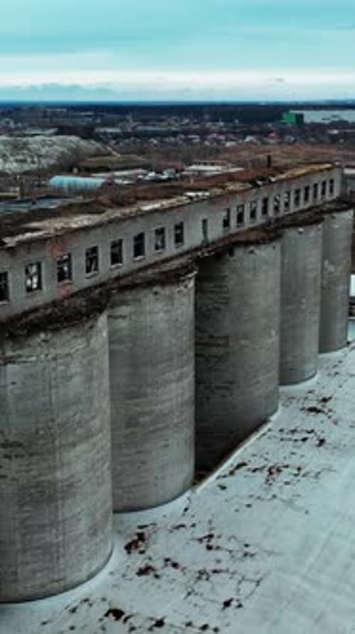 Old chemical plant construction. Ruined long warehouse build on the tops of high concrete reservoirs