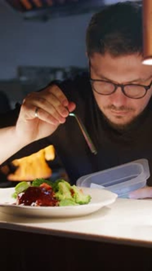 Chef Garnishing Gourmet Dish with Tweezers in Restaurant Kitchen