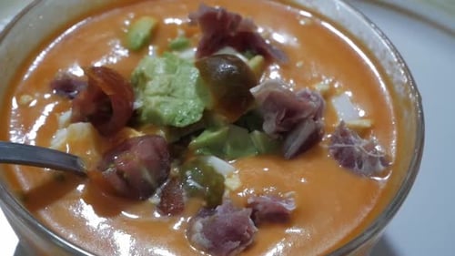 Bowl of gazpacho, traditional tomato soup from Spain. Toppings floating on top, cherry tomatoes, avo