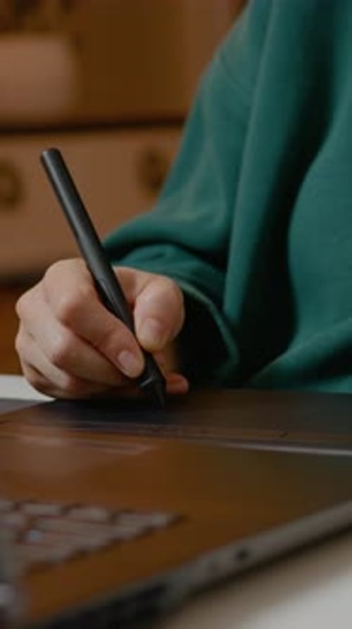 Hand using stylus and graphics tablet with laptop