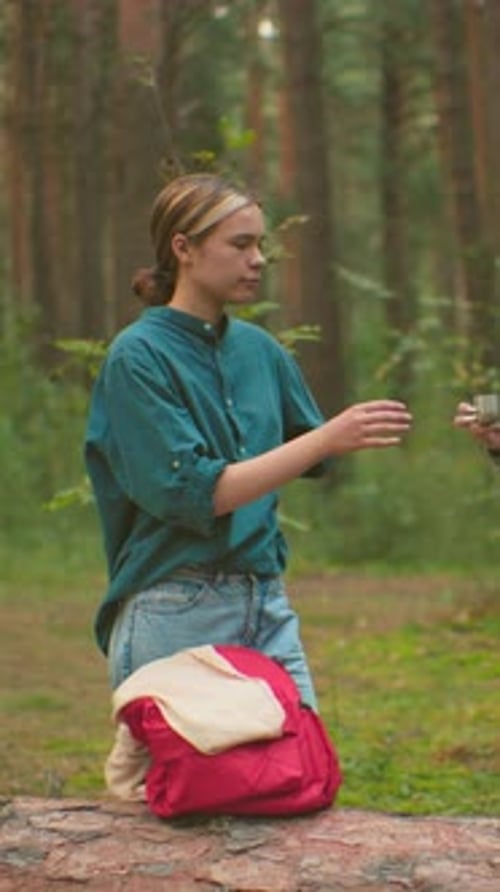 Young Women Enjoy Warm Drink and Friendship in Serene Forest