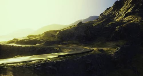 Winding Road Through Dramatic Mountains Bathed in Golden Sunlight