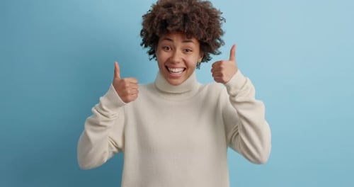 Smiling Woman Gives Two Thumbs Up in Studio