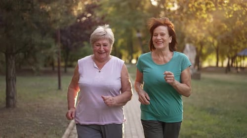 Two Cheerful Elderly Ladies Running at the Park