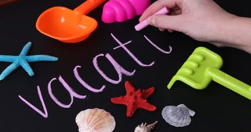 Frau schreibt Wort Urlaub auf Tafel mit Strandspielzeug, Nahaufnahme