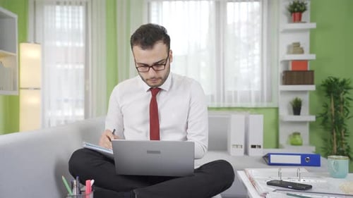 Young Man Video Call on Laptop Taking Notes