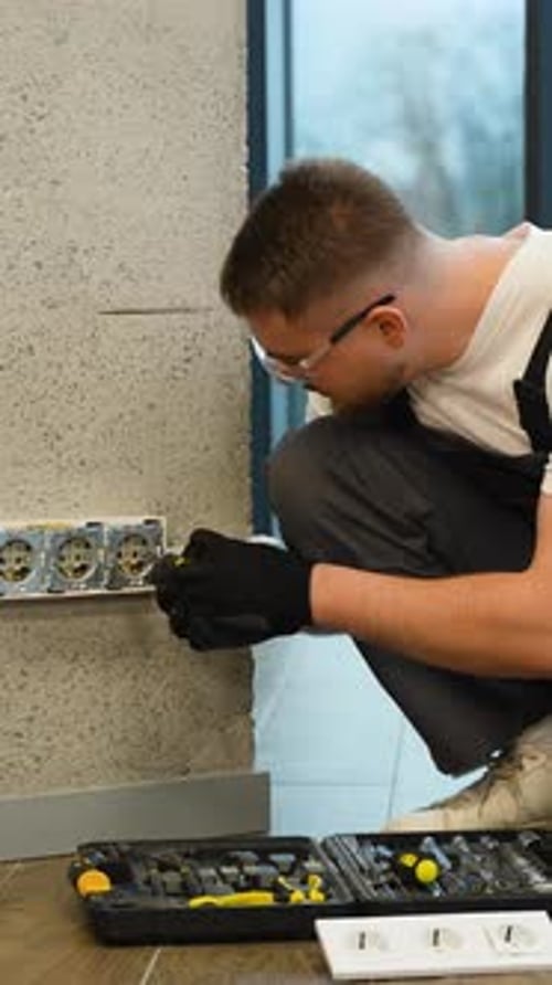 Man Working on Electrical Outlets in Wall