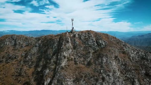 Cinematic Aerial View of a Communication Tower Atop Rugged Mountains