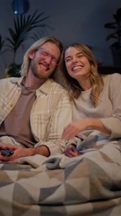 Couple Watching Stand Up and Laughing While Sitting on Sofa