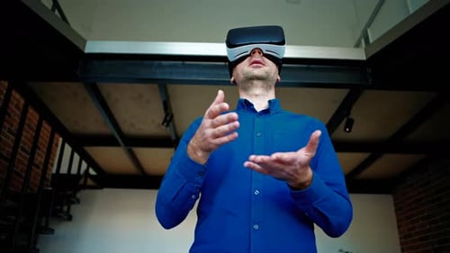 Man gesturing while using a Virtual Reality headset in an office