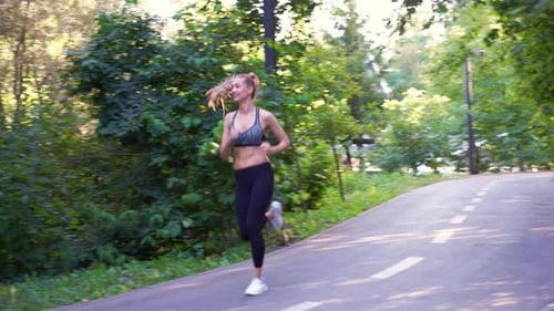 Sporty Woman Jogger Running on Country Road Amidst Trees