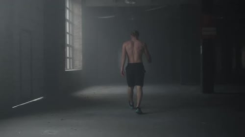 Muscular man walks in loft building after workout tired sportsman warming hands
