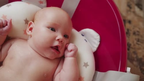 Mother Bathes Her Baby in Pink Bathtub Top View