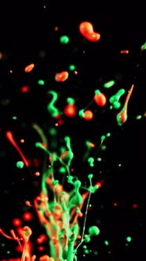 Vivid Neon Orange And Green Paint Particles Splatter On Dark Backdrop