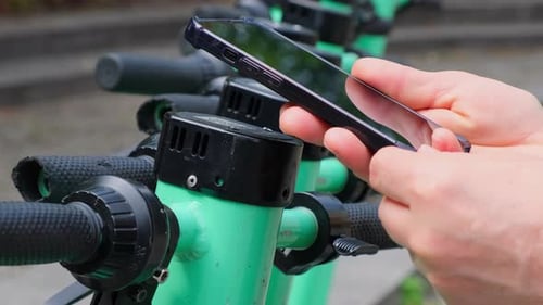 Woman Using App on Smartphone to Unlock Electric Scooter on the Street