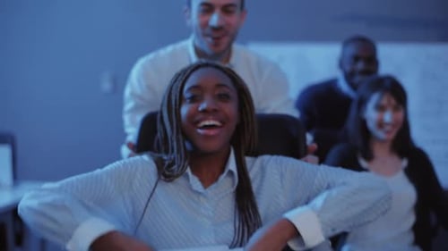 Jovens colegas multiculturais se divertindo em um escritório escuro, garotas rindo e espalhando documentos