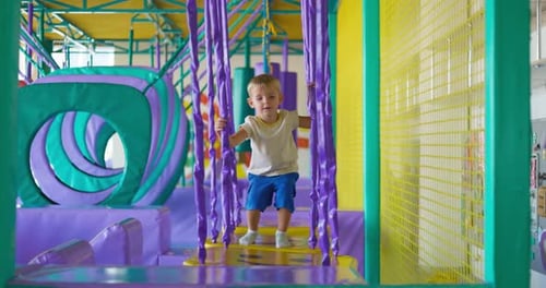 Cute Boy Crawling and Playing on Colorful Playground at Indoor Amusement Park