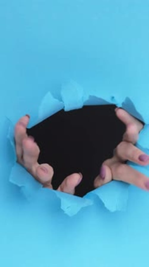 Hands Reaching Through a Hole in Paper