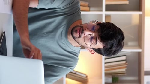 Tired Young Adult Massaging Neck While Working on Laptop