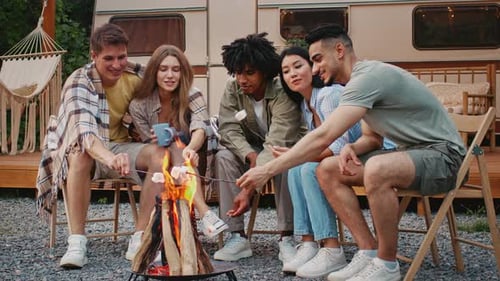 Friends Toasting Marshmallows Around Campfire by Camper