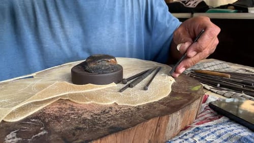 Indonesischer älterer Mann, der geschnitzte handgemachte Wayang-Schattenpuppe herstellt
