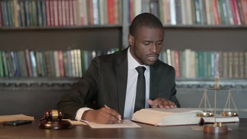 Pensive African Male Lawyer Reading Law Book, Preparing for Court