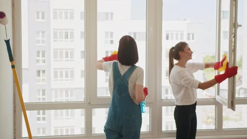 Women Cleaning Windows in a Bright Apartment