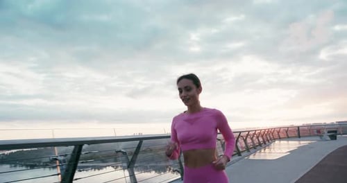 Longhaired Woman Running on Evening Pedestrian Bridge
