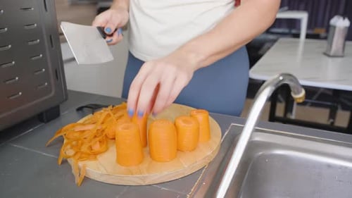 Woman cuts carrots on wood cutting board