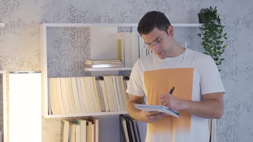 Student Writing in Notebook While Sitting at Desk