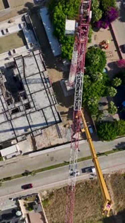 Vertical Video HighAltitude Assembly of a Tower Crane with Workers Securing Metal Sections