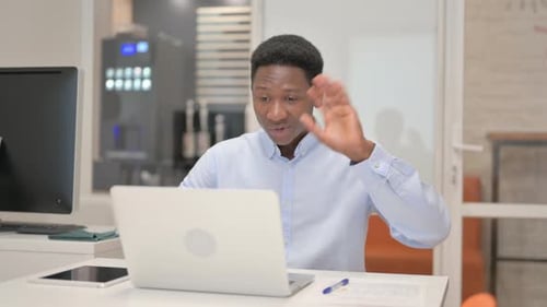 African Businessman Chatting Online on Laptop while Sitting in Office