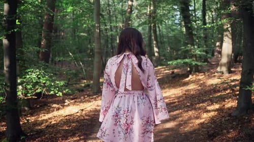 Brunette Girl In Floral Dress Walking On Idyllic Forest At Summertime. Dolly Shot, Slow Motion