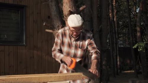 Man Saws Lumber in Rural Outdoor Setting