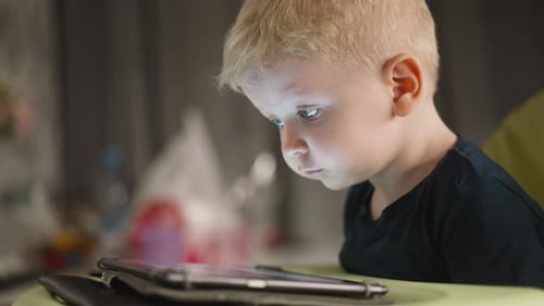 Niño pequeño sonríe mientras ve videos divertidos a través de una tableta