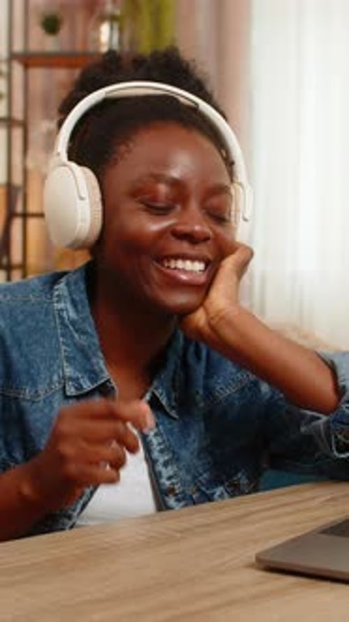 Woman Talking and Smiling Wearing Headphones at Desk
