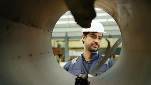 Ingénieur industriel inspectant un gros tuyau métallique en usine. effectuant un contrôle de qualité
