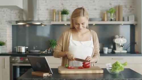 Woman Cuts Red Pepper in Bright Kitchen